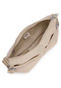 Beige taška Kipling s hladkým povrchem, dvojitými zipovými přihrádkami a logem uvnitř; navržena pro lehké nošení.