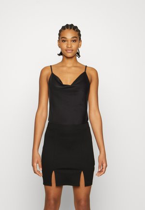 Camisola de cetim preta com alças finas e decote em V, combinada com uma saia mini preta com duas fendas frontais e um design justo.