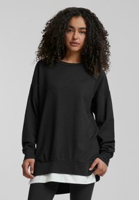 Black long-sleeve sweatshirt with a round neck, relaxed fit, and contrasting white layer at the hem. Soft fabric, minimal detailing, and cuffs.