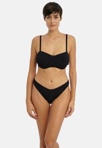 Conjunto de bikini negro que presenta un top tipo bralette texturizado con tirantes finos y una parte inferior de corte alto, que enfatiza una silueta suave y líneas curvas.