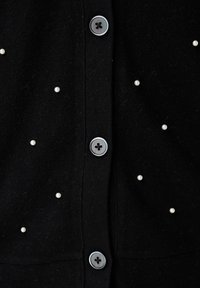 Zwarte cardigan met een zachte textuur, voorzien van ronde grijze knopen en verspreide witte parelversieringen.