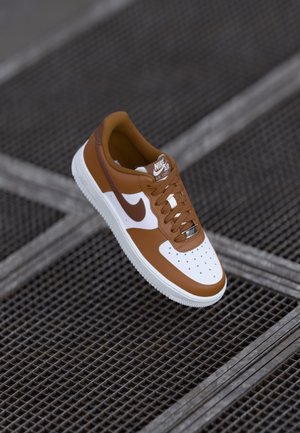 Rudono odinė tenisų bateliai su baltais akcentais, apvalia priekyje, perforacijomis, raištelių uždarymu ir Nike Air logotipu ant liežuvio ir šono. Tekstūruotas padas.