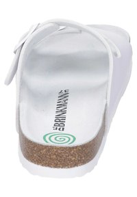 Witte sandaal met een kurken voetbed, textuurgelijke witte band en een gegraveerd logo op de binnenzool, met een ronde vorm en een minimalistisch ontwerp.