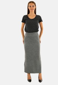 Top de manga corta a rayas en blanco y negro combinado con una falda larga de punto gris con relieve. Ambas prendas tienen un ajuste cómodo y una tela texturizada.