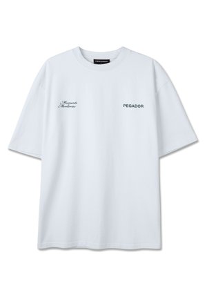 T-shirt blanc à manches courtes avec "Moments Memories" en écriture cursive sur le côté gauche de la poitrine et "PEGADOR" en lettres majuscules sur le côté droit.