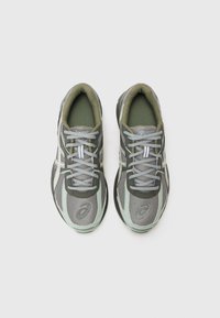 Grey and green athletic shoes with mesh fabric, textured accents, and white stripes. Flexible sole and light gray laces.