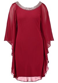 Robe rouge longueur genou avec manches cape transparentes et fluides et encolure ronde ornée de sequins et perles argentés.