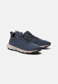 Marinefarbene Mesh-Sneaker mit einer strukturierten Oberseite, verstärkten Ösen und einer hellbeigen Zwischensohle. Verfügt über eine strapazierfähige schwarze Außensohle.