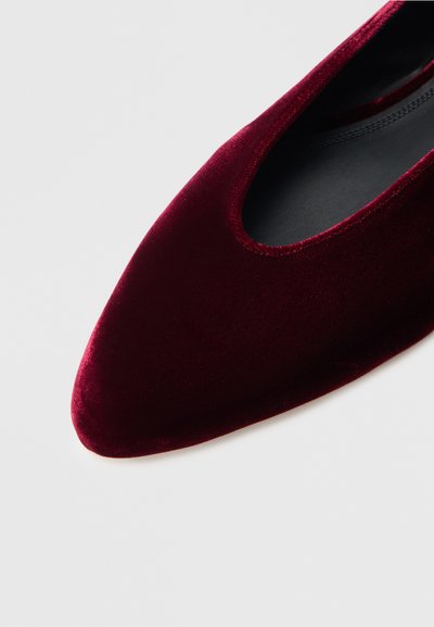 Pantof plat din catifea burgundă cu vârf ascuțit și părți laterale deschise, având căptușeală interioară neagră și textură netedă.