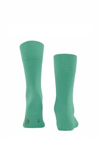 Grüne Baumwollsocken mit glatter Textur, knöchellang und mit geripptem oberen Teil. Mit bedrucktem Text an der Seite nahe dem Knöchel.