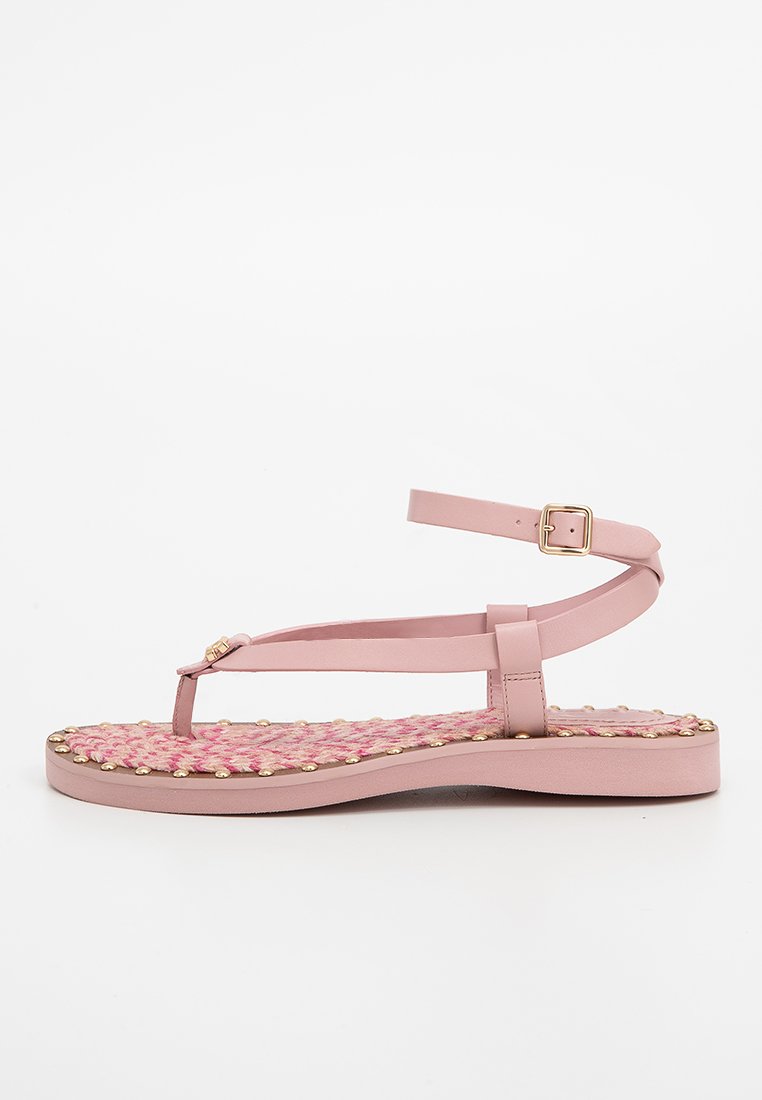 Roze platte sandaal met enkelbandje, gouden gesp, geweven voetbed en kleine gouden studs rond de rand van de zool.