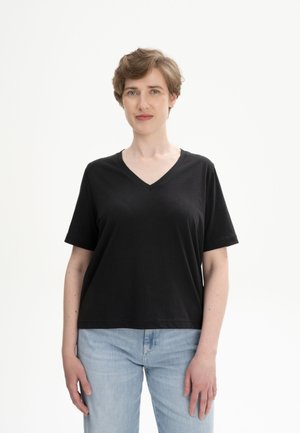 Zwart katoenen V-hals T-shirt met korte mouwen, losse pasvorm, gecombineerd met lichtblauwe jeans. Soepele textuur, minimalistisch ontwerp, geen patronen of accenten.