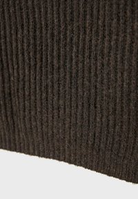 Mörkbrun ribbad tyg med en mjuk textur och fina fibrer, som visar ett konsekvent mönster av vertikala linjer över ytan.