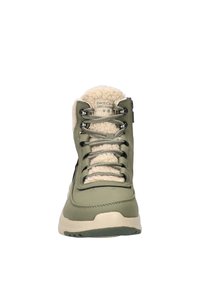 Groene waterdichte laars met een gestructureerde bovenlaag, faux bont voering en metallic veters. Beschikt over een gevoerd zool en een ritsdetail aan de zijkant.