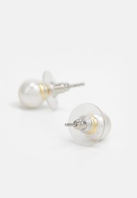 Boucles d'oreilles claires avec des perles blanches ressemblant à des perles, des accents dorés et du matériel en argent. Comprennent des fermoirs transparents pour un maintien sécurisé.