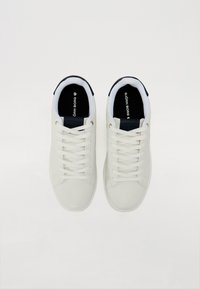 Hvite lær sneakers med en glatt tekstur, rund tå og flate lisser. Har svarte detaljer på hælen og logo på innersålen.
