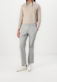 Ljusgrå byxor med skräddarsydd passform, tygblandning, enkla knäppning och sidofickor, kombinerade med vita sneakers och beiget tröja.