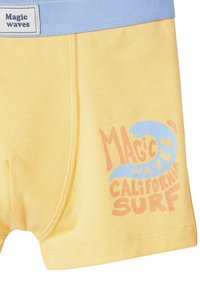 Gelbe und hellblaue Shorts mit dem Text "Magic waves California surf" und einer Wellen-Grafik am rechten Bein sowie einem "Magic waves"-Label am Bund.