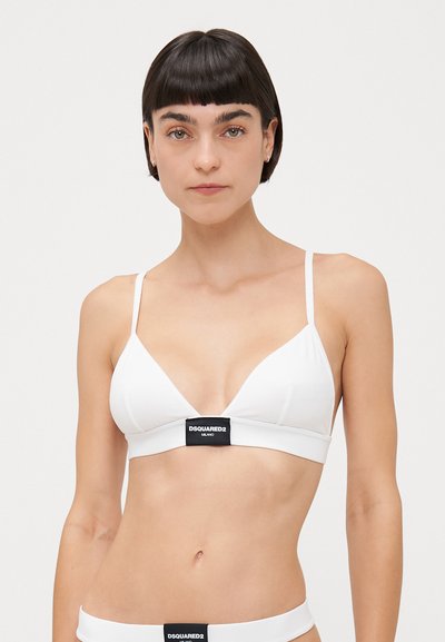 Bralette triangle blanc avec des fines bretelles et une bande logo noire à l'avant. Tissu lisse, design minimaliste.