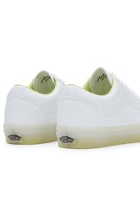 Białe skórzane sneakersy o gładkiej fakturze, zielonym wykończeniu i przezroczystej podeszwie. Posiadają logo na pięcie. Klasyczny fason na sznurowadła.