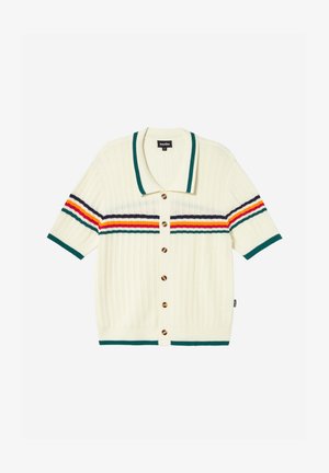 Cardigan lavorato a maglia color crema con maniche corte, colletto e bordi verdi, bottoni marroni e strisce orizzontali verdi, viola, arancioni e gialle su petto e maniche.