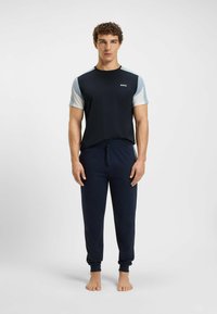 Mansk loungewear-set bestående av en marinblå t-shirt med kort ärm och ljusblå detaljer samt matchande marinblå byxor med dragsko. Tillverkat av bomullsblandning.