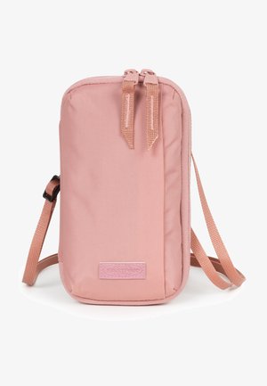 Compact pink nylon crossbody bag with a zippered closure, flat body, adjustable strap, and a branded patch on the front.