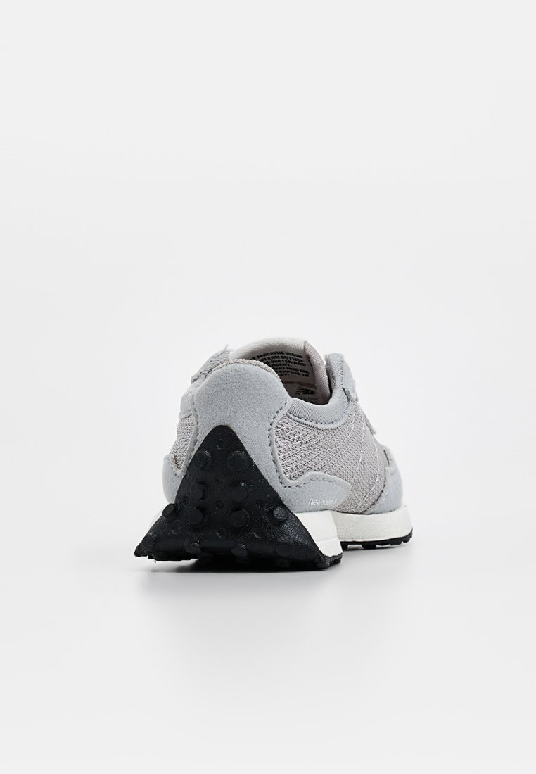 Chaussure de sport grise avec une tige en maille, des accents en suède et une semelle extérieure triangulaire en caoutchouc noir avec des grips circulaires.