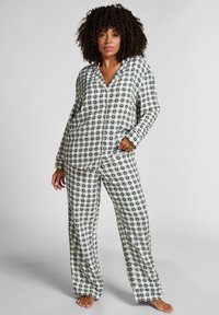 Damski zestaw piżamowy wykonany z lekkiego materiału, z długimi rękawami i luźnym krojem. Wzór zawiera czarno-białą kratę na całej powierzchni.