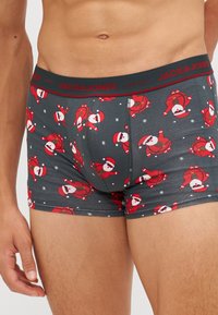 Graue Boxer Briefs mit einem wiederholten Muster von roten Weihnachtsmannfiguren und weißen Schneeflocken. Elastischer Bund mit „JACK & JONES“-Markenlogo.