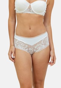 Ensemble de lingerie en dentelle blanche et microfibre comprenant un bralette avec de la dentelle décorative et des culottes taille haute assorties ornées de dentelle florale.