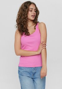 Top aderente rosa con scollatura a barca e spalline sottili, abbinato a jeans azzurri. Il tessuto sembra liscio con una vestibilità elastica.