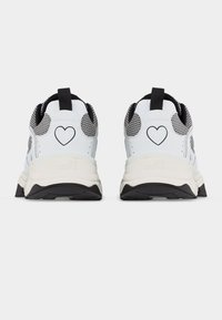 Ζευγάρι λευκά και μαύρα αθλητικά παπούτσια με σχέδιο καρδιάς στο πίσω μέρος και σόλα με τη μάρκα "Love Moschino", εμφανιζόμενα από πίσω.