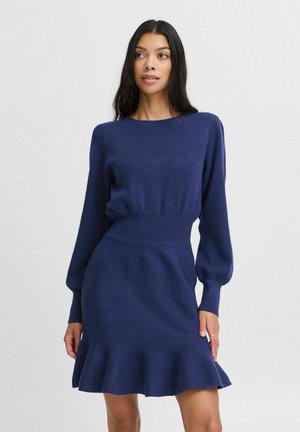 Knit dress in navy blue. Features long puff sleeves, a fitted waist, and a flared hem. Made from a soft, stretchy fabric.