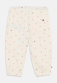 Ανοιχτό μπεζ παντελόνι φόρμας με διασκορπισμένο μοτίβο από ροζ καρδιές, ελαστική μέση και σούρες στα τελειώματα. Περιλαμβάνει λεπτομέρεια με πίσω τσέπη.