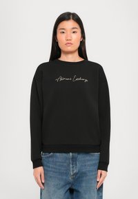 Zwarte sweatshirt met een ronde halslijn en geribbelde manchetten. Heeft "Armani Exchange" in gouden cursieve borduursel aan de voorkant.