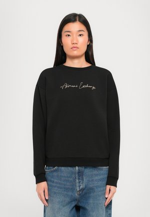Mustapaita, jossa on pyöreä kaula-aukko ja ribbatut hihansuut. Etupuolella kultaisella kierrettynä kirjailtuna "Armani Exchange".