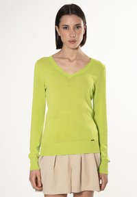 V-Ausschnitt, langärmliger Pullover in leuchtendem Limettengrün, aus leichtem Strickmaterial mit gerippten Bündchen und Saum, versehen mit einem dezenten Logodetail.