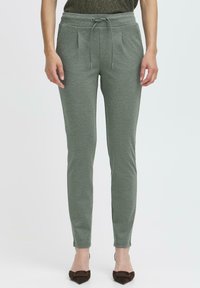 Zielone, tapered joggery w miękkim materiale. Posiadają elastyczny pas ze sznurkiem, kieszenie boczne oraz przody z zakładkami. Gładka tekstura i dopasowany krój.