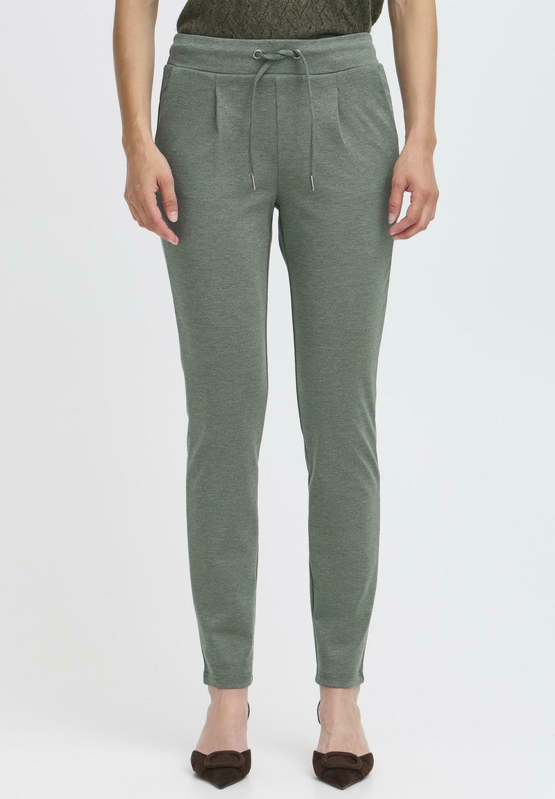Grønne, tapered joggerbukser i blødt stof. Har en elastisk talje med snor, sidelommer og frontfold. Glat tekstur og tætsiddende design.