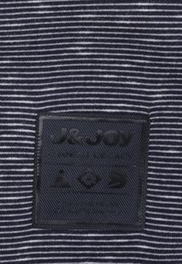 Donkerblauwe en witte gestreepte stof met een gestikt donker label waarop staat "J&JOY Andean Legacy from the heart of South America."