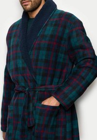 Rutig badekåbe i mørkegrøn, marineblå og rød. Fremstillet af blødt stof med en fyldig krave, bælte i taljen og sidelommer. Har en afslappet pasform.