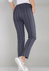 Grijze broek met streepjespatroon, voorzien van een rekbare tailleband, tapered fit en een gladde textuur. Gemaakt in combinatie met lichtgekleurde platform schoenen.