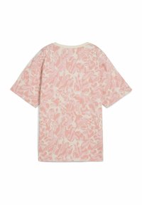 Camiseta rosa con estampado, de mangas cortas y corte relajado. El diseño presenta formas abstractas en tonos de rosa claro y oscuro sobre un fondo crema.