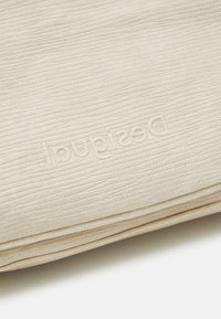 Beige Leder Geldbörse mit strukturierten Oberflächen und eingeprägtem Logo. Sie zeichnet sich durch ein schlankes Design mit sichtbaren genähten Kanten aus.