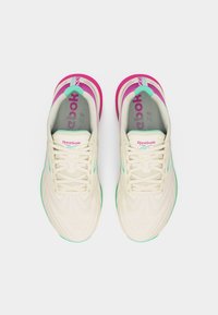 Ζεύγος κρεμ αθλητικών παπουτσιών Reebok με ροζ και τιρκουάζ λεπτομέρειες και κορδόνια, απεικονιζόμενα από την κορυφή σε λευκό φόντο.