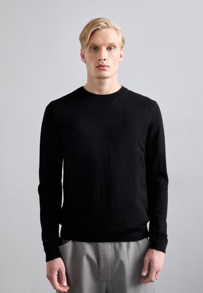 Schwarzer gestrickter Pullover mit rundem Ausschnitt, langen Ärmeln und gerippten Bündchen. Der Stoff wirkt glatt und hat eine weiche Textur.