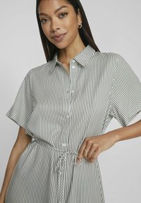 Pruhované košilové šaty v světle šedé a tmavě zelené barvě, s krátkými rukávy, páskem na zavázání v pase a límečkem. Měkká textilie.