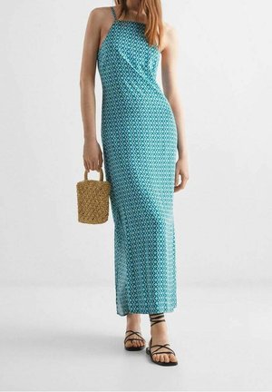 Maxi dress turchese con motivo geometrico e scollatura a halter. Accessoriato con una piccola borsa intrecciata e sandali flat.