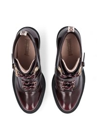 Bordeauxfarbene Leder-Ankle-Boots mit kontrastierenden Schnürsenkeln, goldenen Hardware-Akzenten und einer strukturierten schwarzen Gummisohle. Draufsicht zur Präsentation der Designdetails.